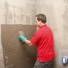 A man is applying adhesive to a wall with a trowel. Náhľad obrázku produktu