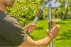 A person is using a telescopic lopper in a garden setting. Produktbild-Vorschau