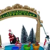 A festive Christmas scene with miniature figures, including Santa Claus, a snowman, and children in rotating coffee cups, set against a backdrop of snow-covered trees and a decorative archway. Náhled obrázku produktu