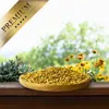 A wooden bowl filled with birdseed sits on a wooden surface, with a blurred background of greenery and flowers. A 'PREMIUM' banner is in the top left corner. Produktbild-Vorschau