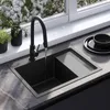 A black sink with a faucet running water, set against a window with blooming flowers. Anteprima dell’immagine prodotto