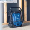 A blue and black Scheppach S800 hand sweeper is shown standing on a concrete surface in front of a dark wall and wooden beams. Náhľad obrázku produktu