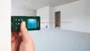 A hand holding a laser distance measurer in an unfinished room. Produktbild-Vorschau