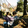 Children on a swing set in a backyard during autumn. Voir les images du produit