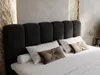 A close-up view of a bed with a black upholstered headboard and white bedding. Produktbild-Vorschau