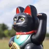 A close-up of a black Maneki-neko (waving cat) statue with red ears and collar, holding a gold coin. Produktbild-Vorschau