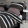 A close-up view of a bed with striped bedding and pillows. Produktbild-Vorschau
