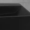 A close-up view of a black ceramic sink with a textured gray tiled wall in the background. Podgląd zdjęcia produktu