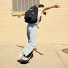 A person is skateboarding while wearing a backpack. Náhľad obrázku produktu