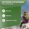 A person sitting on a rock in a mountainous landscape, using an outdoor seat cushion. Produktbild-Vorschau