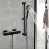 A black thermostatic shower mixer system mounted on a grey tiled wall. Náhled obrázku produktu