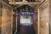 Interior of a rustic wooden bar or cabin with a bar counter and shelves stocked with bottles and glasses. Produktbild-Vorschau