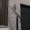 A black metal handrail is shown attached to a brick wall next to a dark garage door. Produktbild-Vorschau