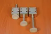 Three adjustable furniture feet with threaded bolts and white plastic caps are arranged on a wooden surface. Produktbild-Vorschau