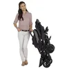 A woman stands next to a folded stroller. Voir les images du produit