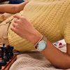 A person's arm wearing a watch and bracelet, resting on a striped blanket next to a chessboard. Voir les images du produit