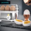 A close-up shot of boiled eggs, one sliced in half, next to an egg cooker and an egg cup. Podgląd zdjęcia produktu