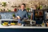 A man in a kitchen holding a frying pan. Produktbild-Vorschau