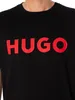 A close-up shot of a person wearing a black t-shirt with a large red "HUGO" logo printed on the front. Produktbild-Vorschau