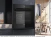 A modern kitchen scene featuring a built-in oven and a dining area. Produktbild-Vorschau