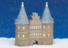 A miniature, illuminated castle-like building, likely a Christmas village decoration, sits in the snow under a starry night sky. Produktbild-Vorschau