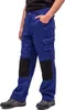 A person wearing blue work pants with black knee patches and grey and brown work boots, shown from the side. Produktbild-Vorschau