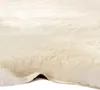 A close-up view of a white sheepskin rug, showing its texture and thickness. Voir les images du produit