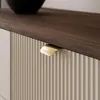 Close-up of a modern dresser with a fluted front and a brass handle. Produktbild-Vorschau