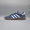 A side view of a navy blue Adidas Handball Spezial sneaker against a plain gray background. Voir les images du produit