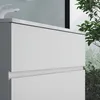 A close-up view of a white bathroom vanity with two drawers, set against a light gray wall and a window with greenery outside. Produktbild-Vorschau