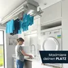 A woman is doing laundry in a modern laundry room with a ceiling-mounted clothes dryer. Produktbild-Vorschau