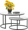 A set of two round nesting coffee tables with white marble-look tops and black metal frames. A bouquet of yellow and green flowers in a black vase sits on the larger table, next to two stacked books. Voir les images du produit