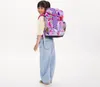 A young girl wearing a backpack stands against a white background. Produktbild-Vorschau