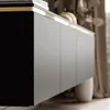 Close-up of a modern cabinet with clean lines and a subtle gold accent, in a softly lit room with draped curtains. Produktbild-Vorschau
