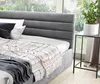 A close-up view of a bed with a gray upholstered headboard and a patterned throw blanket. Produktbild-Vorschau