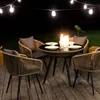 An outdoor patio set with chairs and a table illuminated by string lights at night. Náhled obrázku produktu