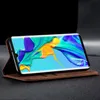 A smartphone in a brown leather flip case is displayed on a dark surface, with the phone's screen showing a colorful abstract image. Produktbild-Vorschau