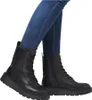 A pair of black lace-up boots worn by a person in blue jeans, shown from the knees down against a white background. Podgląd zdjęcia produktu