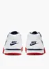 The back view of two white Nike Cross Trainer Low sneakers with navy and red accents, set against a white background. Náhled obrázku produktu