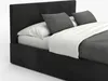 A close-up view of a bed with a dark gray upholstered headboard and frame, white sheets, and two gray decorative pillows. Produktbild-Vorschau