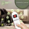 A hand holding a white remote control for an electric blanket, with temperature settings displayed around it. A blurred background shows a living room setting with a sofa and blanket. Produktbild-Vorschau