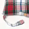 A close-up view of a plaid cushion with a button and a fabric tie. Náhled obrázku produktu