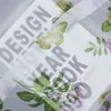 A close-up view of a transparent fabric with floral and butterfly patterns, overlaid on text. Produktbild-Vorschau