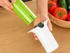 Hands are shown assembling a vegetable slicer, with a basket of tomatoes and cucumbers in the background. Podgląd zdjęcia produktu