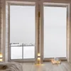 Two white pleated blinds are shown covering windows in a room with wooden walls and floor. The blinds are partially lowered, revealing a snowy outdoor scene through the left window. Decorative candles are placed on a tray on the floor in front of the right Produktbild-Vorschau
