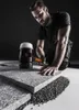 A man is kneeling and using a rubber mallet to install a stone paver. Náhľad obrázku produktu