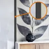A close-up view of a decorative vase on a cabinet, with a magnified section of a wall art piece. Podgląd zdjęcia produktu