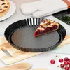 A slice of cherry pie sits in a fluted tart pan on a wooden cutting board, with a whole pie and oven mitt in the background. Produktbild-Vorschau