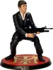 A figurine of Tony Montana from Scarface holding a gun, standing on a red circular base with the Scarface logo. Podgląd zdjęcia produktu