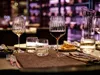 A table setting with wine glasses, a carafe, and food in a restaurant or bar setting. Náhled obrázku produktu